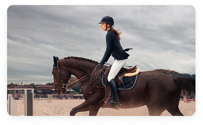 Cavaleira a montar um cavalo numa pista de treino equestre