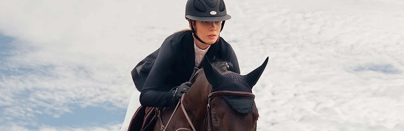 Cavaleira a ultrapassar um obstáculo com o seu cavalo durante uma competição
